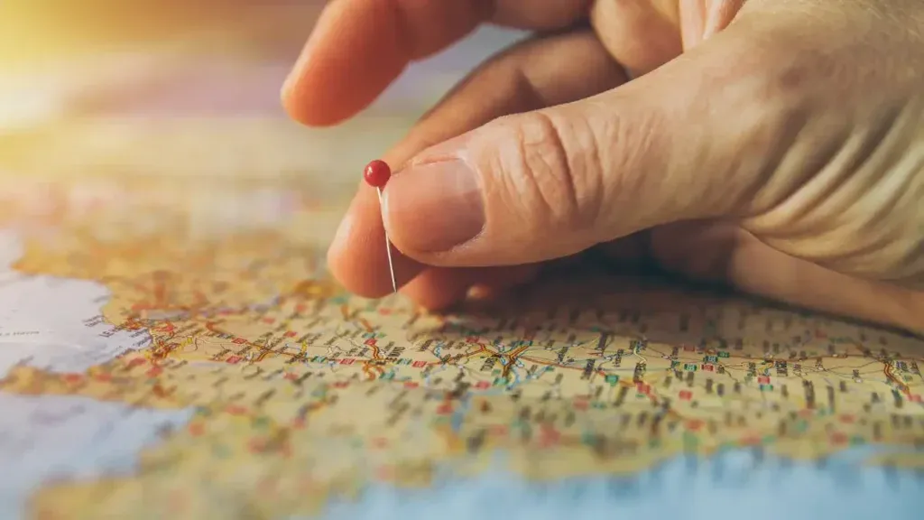 Hand placing a red pin on a UK map to represent franchise location choice
